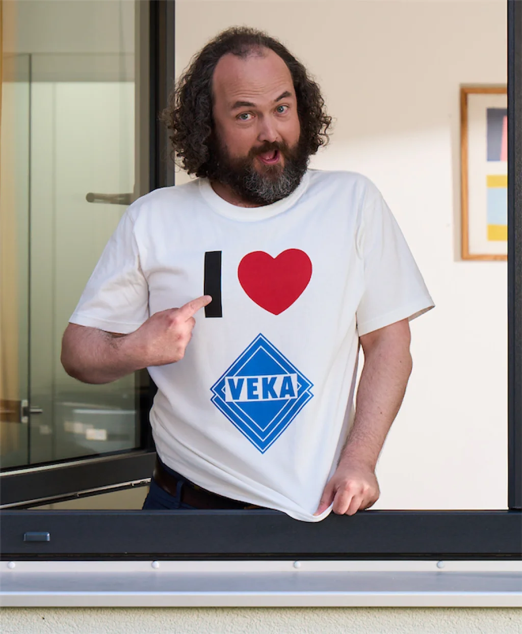Holger zeigt auf sein VEKA T-Shirt Holger trägt ein -T-Shirt mit I love VEKA.
